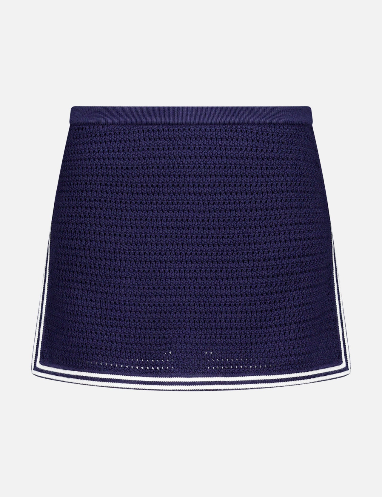 The Monique Knit Mini Skort by AMANDA UPRICHARD features a navy blue crochet design, fitted silhouette, and white trim on the hem and sides, offering both elegance and comfort. Displayed against a plain white background.
