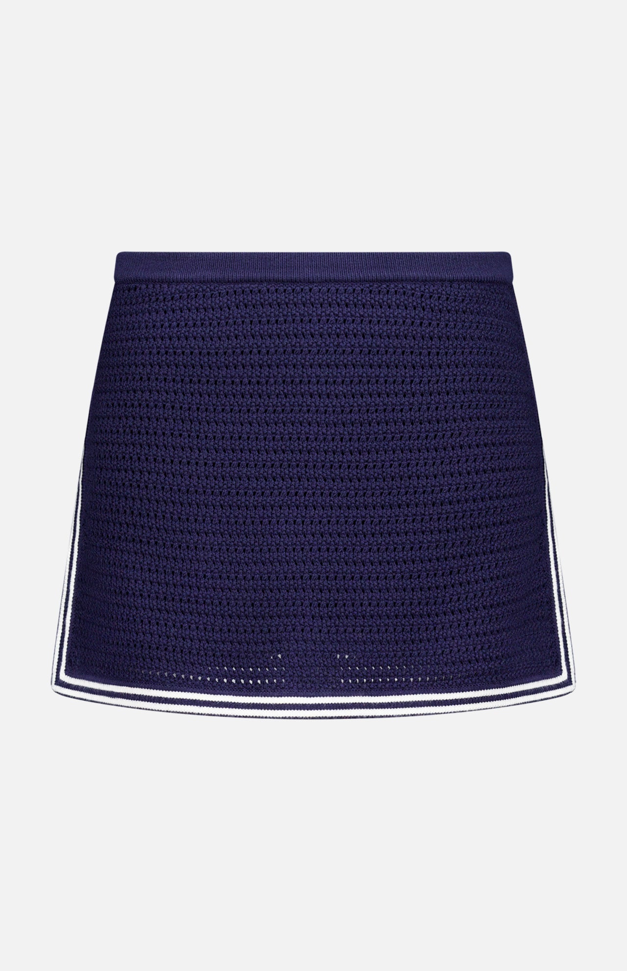 The Monique Knit Mini Skort by AMANDA UPRICHARD features a navy blue crochet design, fitted silhouette, and white trim on the hem and sides, offering both elegance and comfort. Displayed against a plain white background.