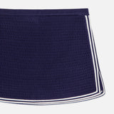 The AMANDA UPRICHARD Monique Knit Mini Skort is a navy, fitted skort with white striped trim along the sides and bottom edges, displayed against a white background.