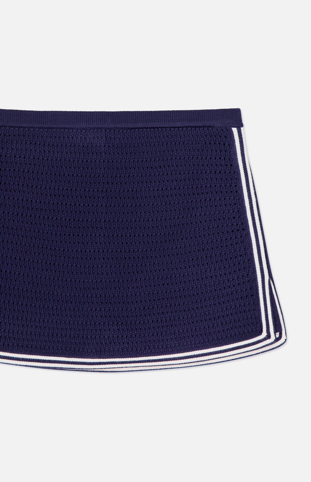 The AMANDA UPRICHARD Monique Knit Mini Skort is a navy, fitted skort with white striped trim along the sides and bottom edges, displayed against a white background.