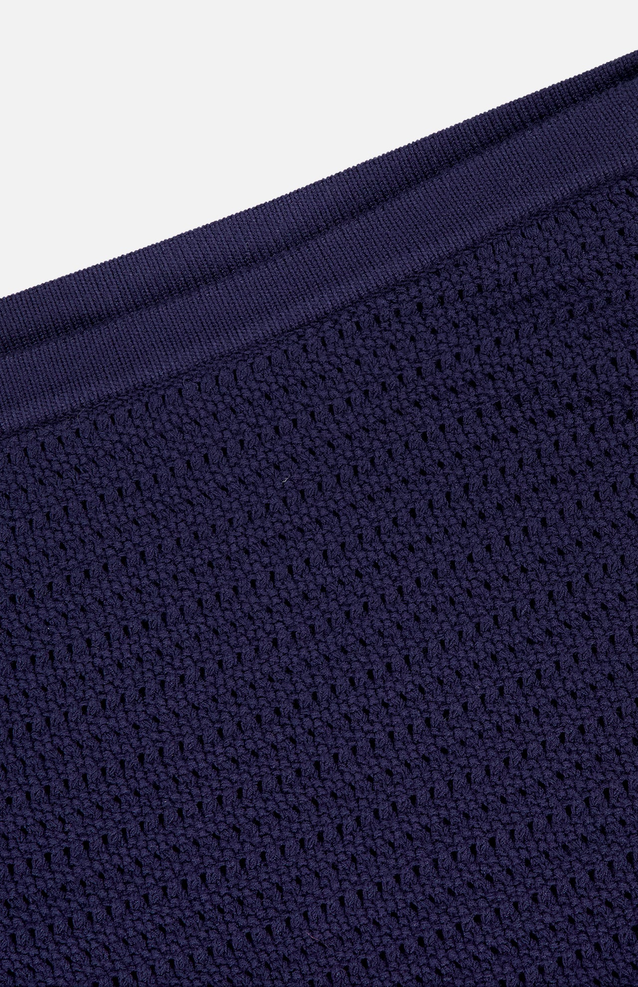 Close-up of the Monique Knit Mini Skort by AMANDA UPRICHARD, featuring textured dark navy knit fabric with a waffle-like pattern and diagonal ribbed edge, highlighting its fitted silhouette and built-in shorts.