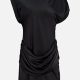 The Olandria Waist Bustle Mini Dress by AMANDA UPRICHARD is a black satin cocktail dress featuring a loose, draped cowl detail at the waist, short sleeves, and a simple round neckline, shown against a plain white background.