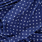 Close-up of the Rumi Sleeveless Polka Dot Dress by AMANDA UPRICHARD, featuring blue fabric with white dots, gathered ruched details for added texture, and a light, slightly sheer material for an airy feel.