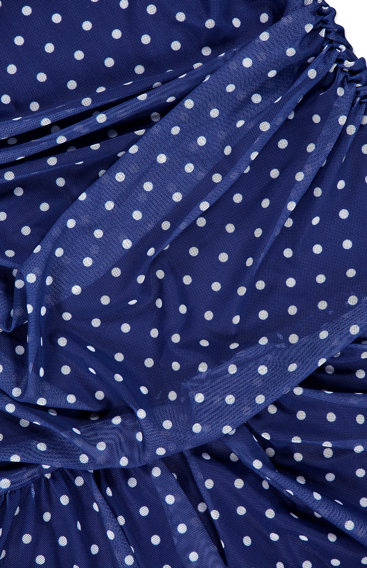 Close-up of the Rumi Sleeveless Polka Dot Dress by AMANDA UPRICHARD, featuring blue fabric with white dots, gathered ruched details for added texture, and a light, slightly sheer material for an airy feel.