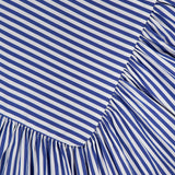 Close-up of blue and white diagonal stripes on the Spencer Striped Midi Dress by AMANDA UPRICHARD, featuring an angled seam and gathered, ruffled fabric below—perfect for a summer party look.