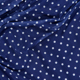The Zoey Polka Dot Midi Dress by AMANDA UPRICHARD features dark blue fabric with evenly spaced white polka dots, draping in soft, uneven folds for a timeless and classic look.