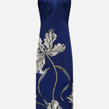 The Amani Maxi Halter Neck Dress by ANDRÉS OTÁLORA is a navy blue, strapless halter dress with a gathered bust and a white-gray floral pattern featuring large leaves and winding stems near the hem.