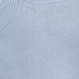 Close-up of ANDRÉS OTÁLORA's Amari Ama Linen Mini Dress in baby blue, showing smooth linen fabric with a subtle crosshatch pattern and raised, concentric stitched lines curving at the top left.