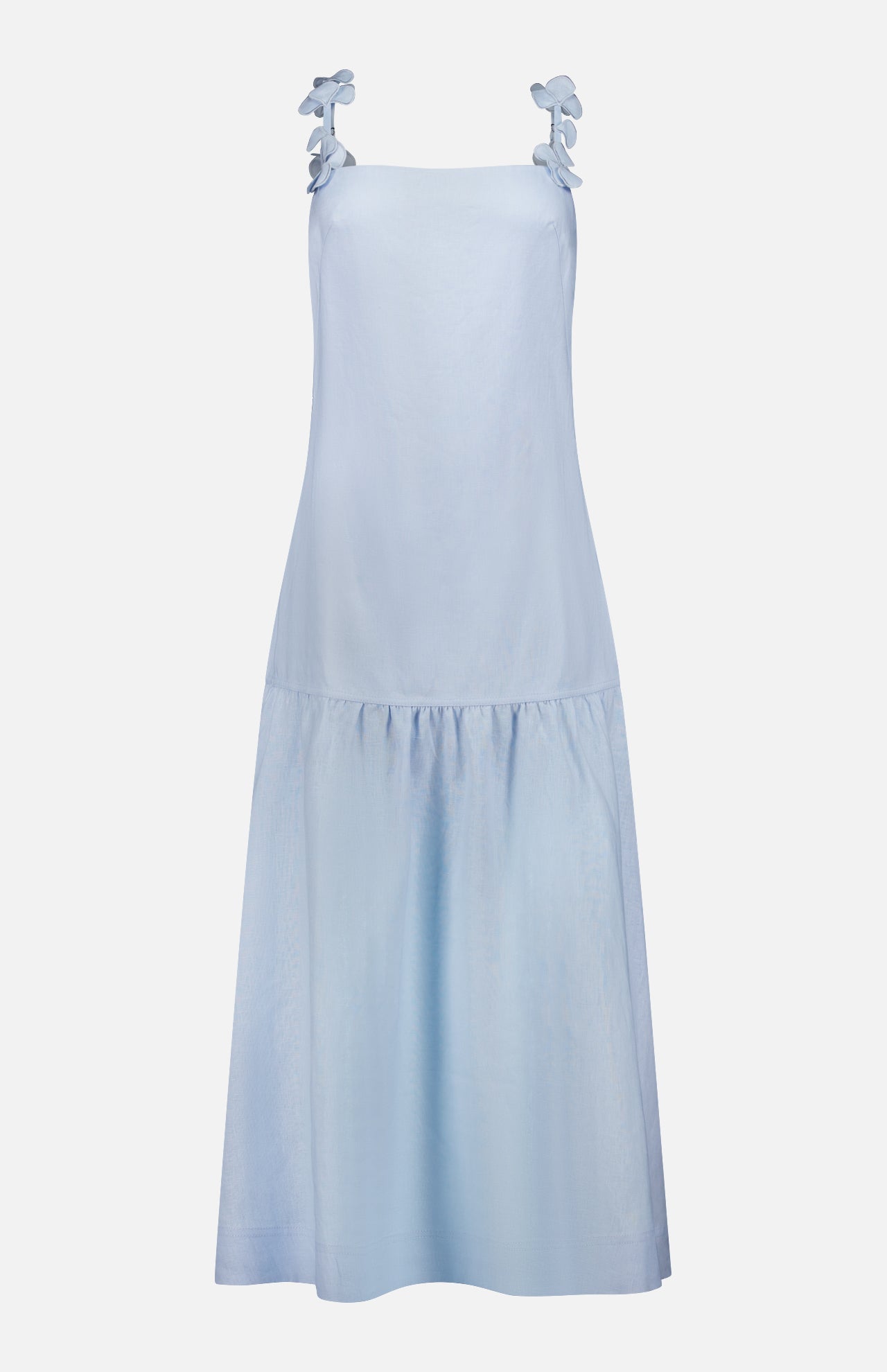 The Benditas Maxi Linen Dress by ANDRÉS OTÁLORA is a Mediterranean-inspired, sleeveless light blue dress with wide shoulder straps, decorative bows, and a drop waist. This knee-length baby blue dress is shown against a plain white background.