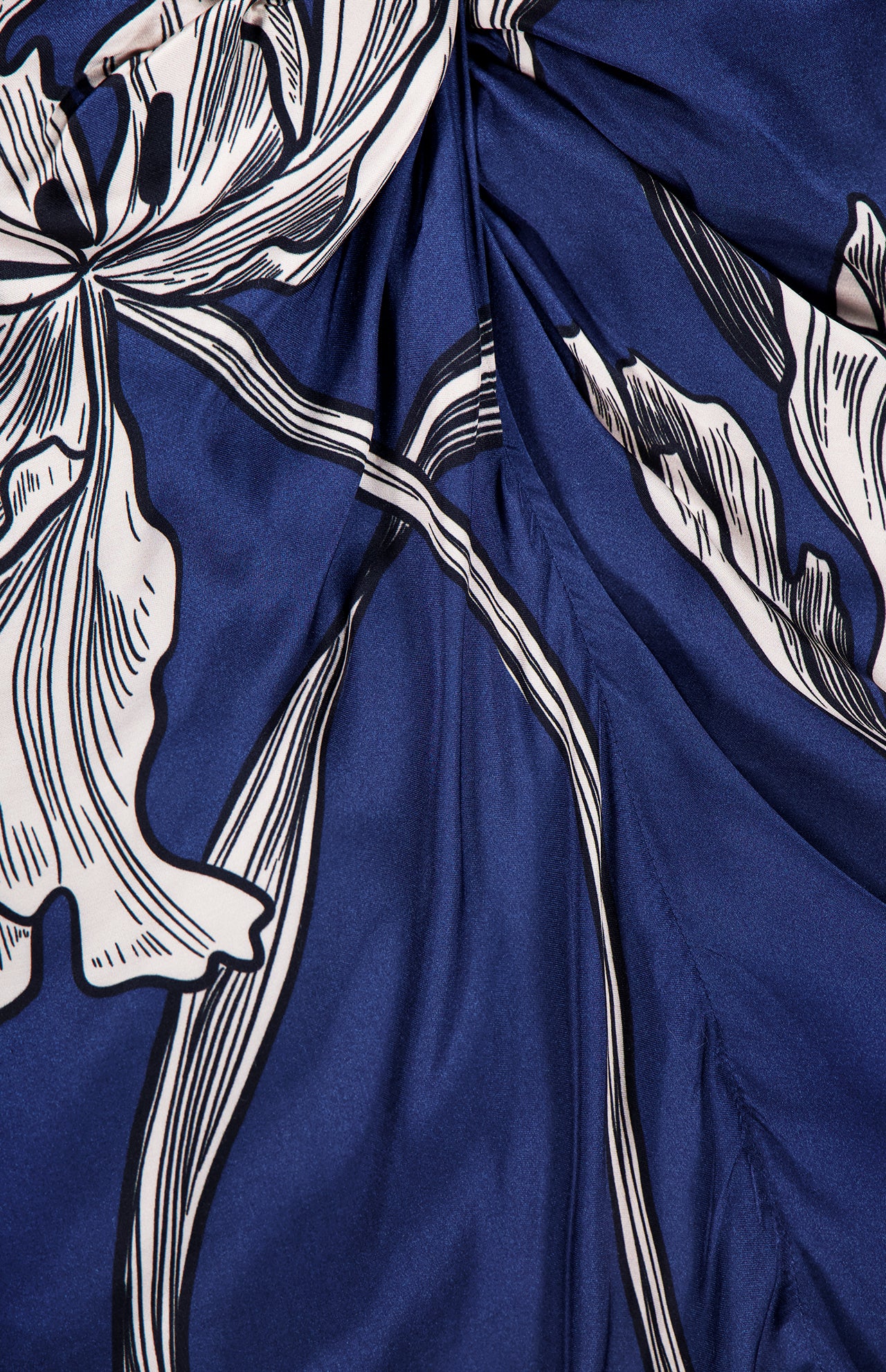 A close-up of blue fabric from the Olanna Twist Front Maxi Dress by ANDRÉS OTÁLORA, showcasing a Mediterranean-inspired white and black botanical print with stylized leaves and flowing, bold lines.