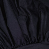 Close-up of the Tan Lejos Top by ANDRÉS OTÁLORA, featuring sculptural black fabric with gathered details, visible folds and pleats for a textured, slightly shiny finish.