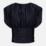 The Tan Lejos Top by ANDRÉS OTÁLORA is a sculptural black short-sleeved blouse with ruching, a wide gathered neckline, and fitted pleated waistband—an elegant going-out top shown on a plain white background.