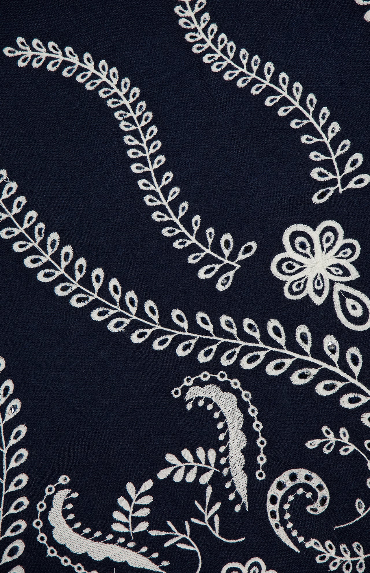 The Y Tu Voz Eyelet Dress by ANDRÉS OTÁLORA is a navy blue linen dress embroidered with white floral and paisley patterns, featuring curving vines, leaves, and stylized flower details.