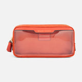 Anya Hindmarch Beach Things Pouch, a rectangular orange zippered travel case with a transparent front panel, embossed text at the top, and a small tassel on the side.