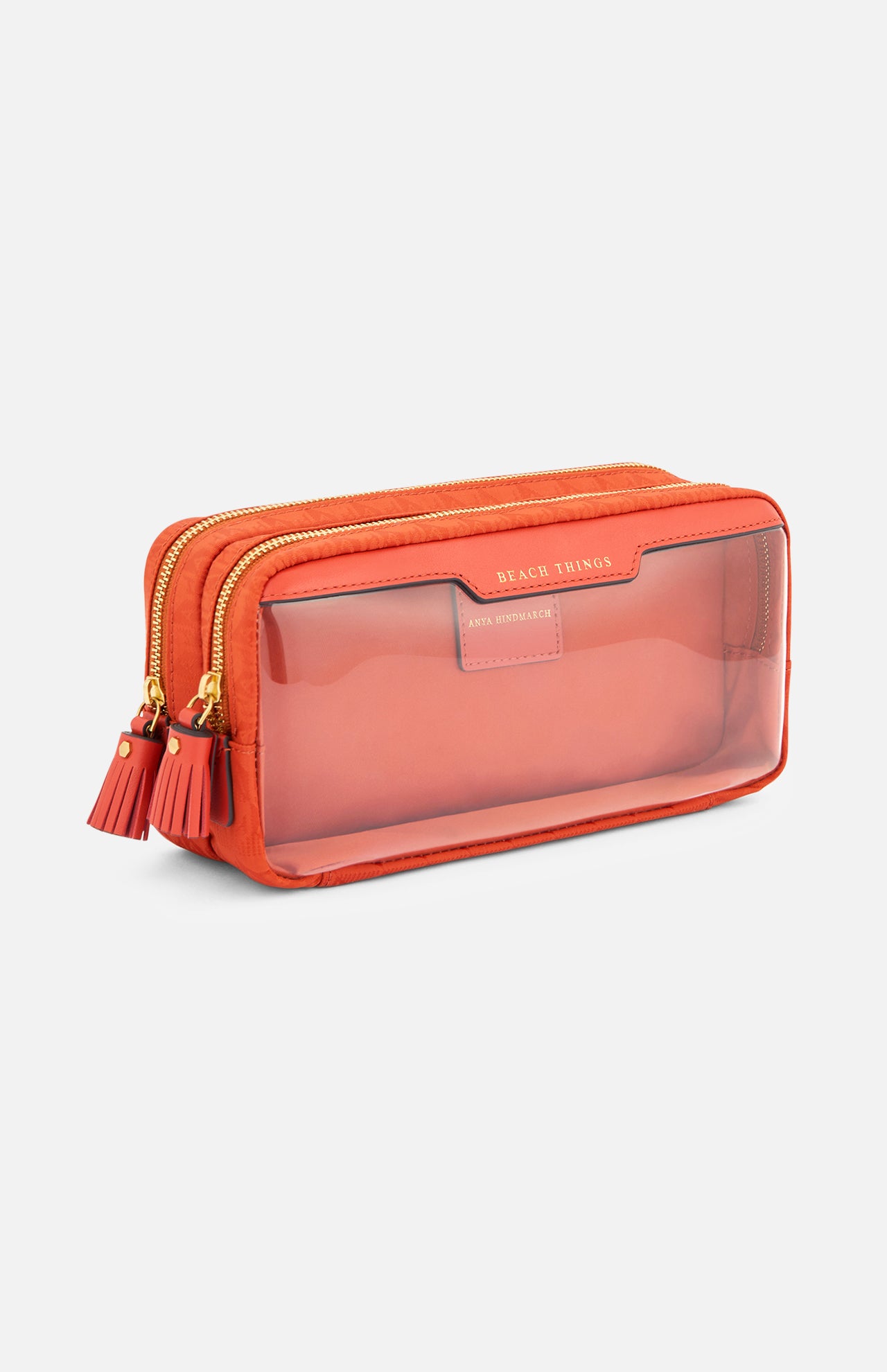 Anya Hindmarch Beach Things Pouch, a rectangular orange travel pouch featuring a clear front panel and two tassel-ended zipper pulls.
