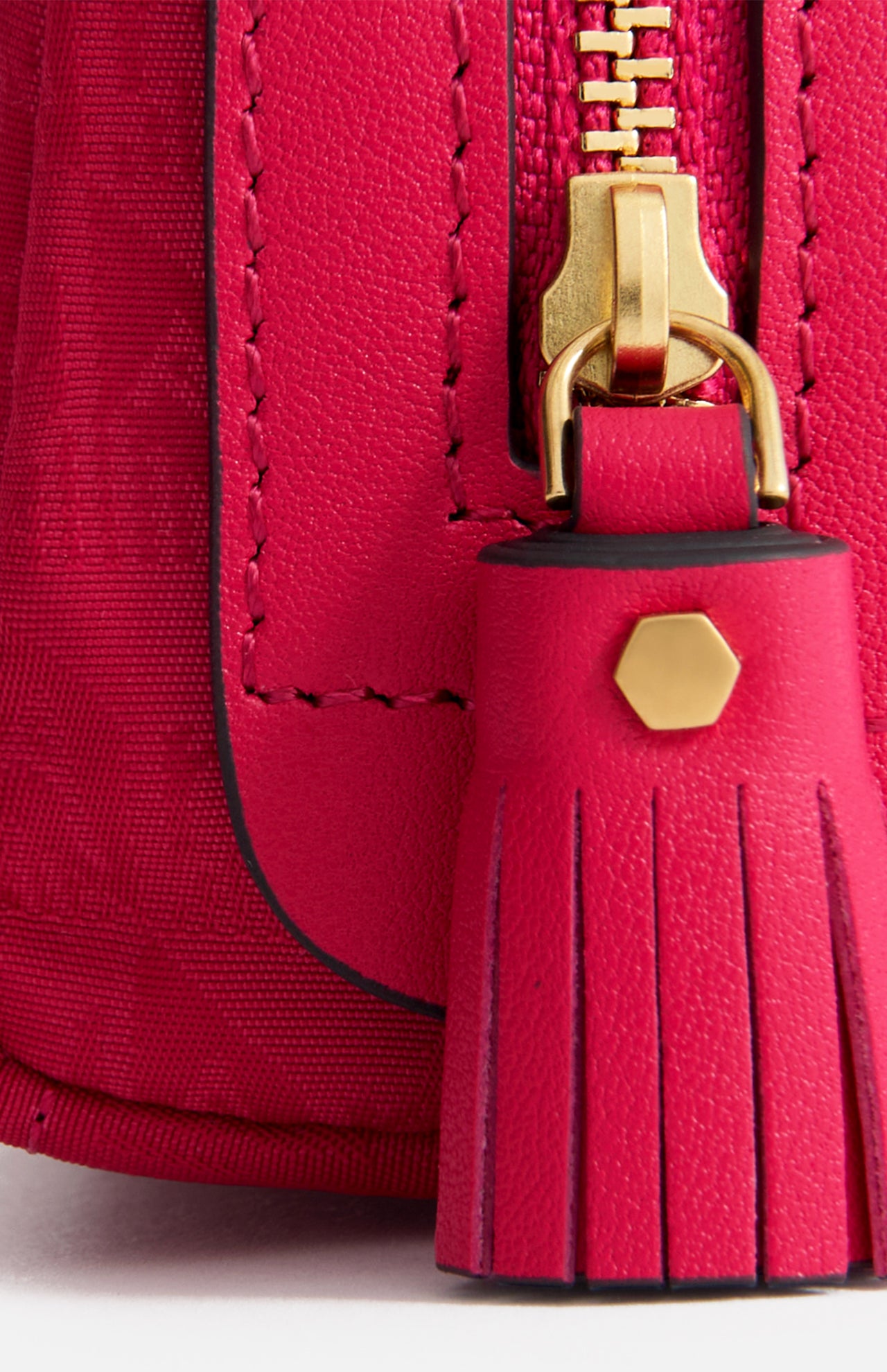 Close-up of a hot pink jacquard nylon Logo Girlie Stuff Pouch by Anya Hindmarch with a matching leather tassel pull and gold hardware.