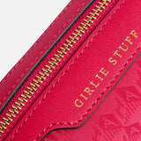 A close-up of a pink Anya Hindmarch Logo Girlie Stuff Pouch featuring a zipper and the words GIRLIE STUFF embossed in gold.