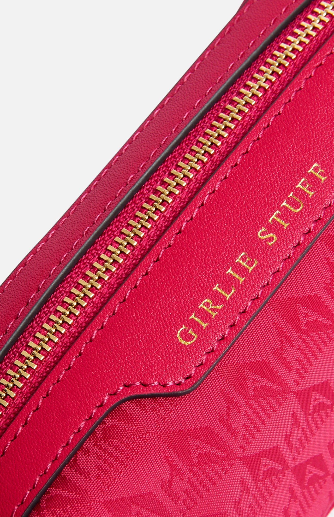 A close-up of a pink Anya Hindmarch Logo Girlie Stuff Pouch featuring a zipper and the words GIRLIE STUFF embossed in gold.