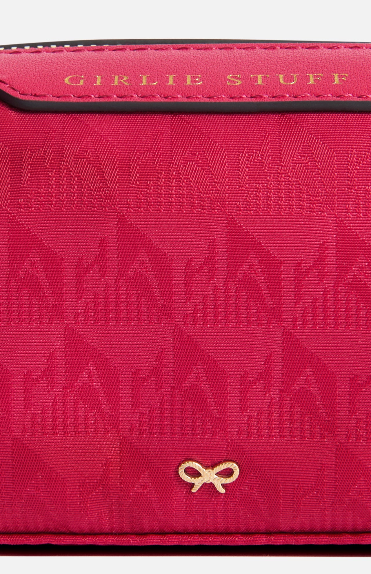 Anya Hindmarch Logo Girlie Stuff Pouch in hot pink jacquard nylon with black leather trim embossed with the words GIRLIE STUFF, featuring a gold bow-shaped logo at the bottom.