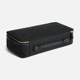 Anya Hindmarch Logo Hair Kit Travel Pouch, a black rectangular hair tools organizer with a top handle and a gold-tone wraparound zipper.