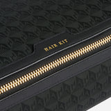 Anya Hindmarch Logo Hair Kit Travel Pouch in black with a repeating pattern and a zippered closure labeled HAIR KIT in gold lettering.