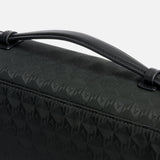 Anya Hindmarch Logo Hair Kit Travel Pouch in black, featuring a repeating geometric logo pattern, a top carry handle, and a spacious interior ideal as a hair tools organizer.