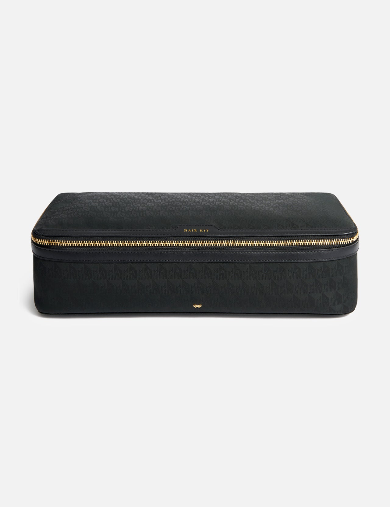 Anya Hindmarch Logo Hair Kit Travel Pouch, a black rectangular case with a wrap-around gold zipper and the text HAIR KIT centered on the front.