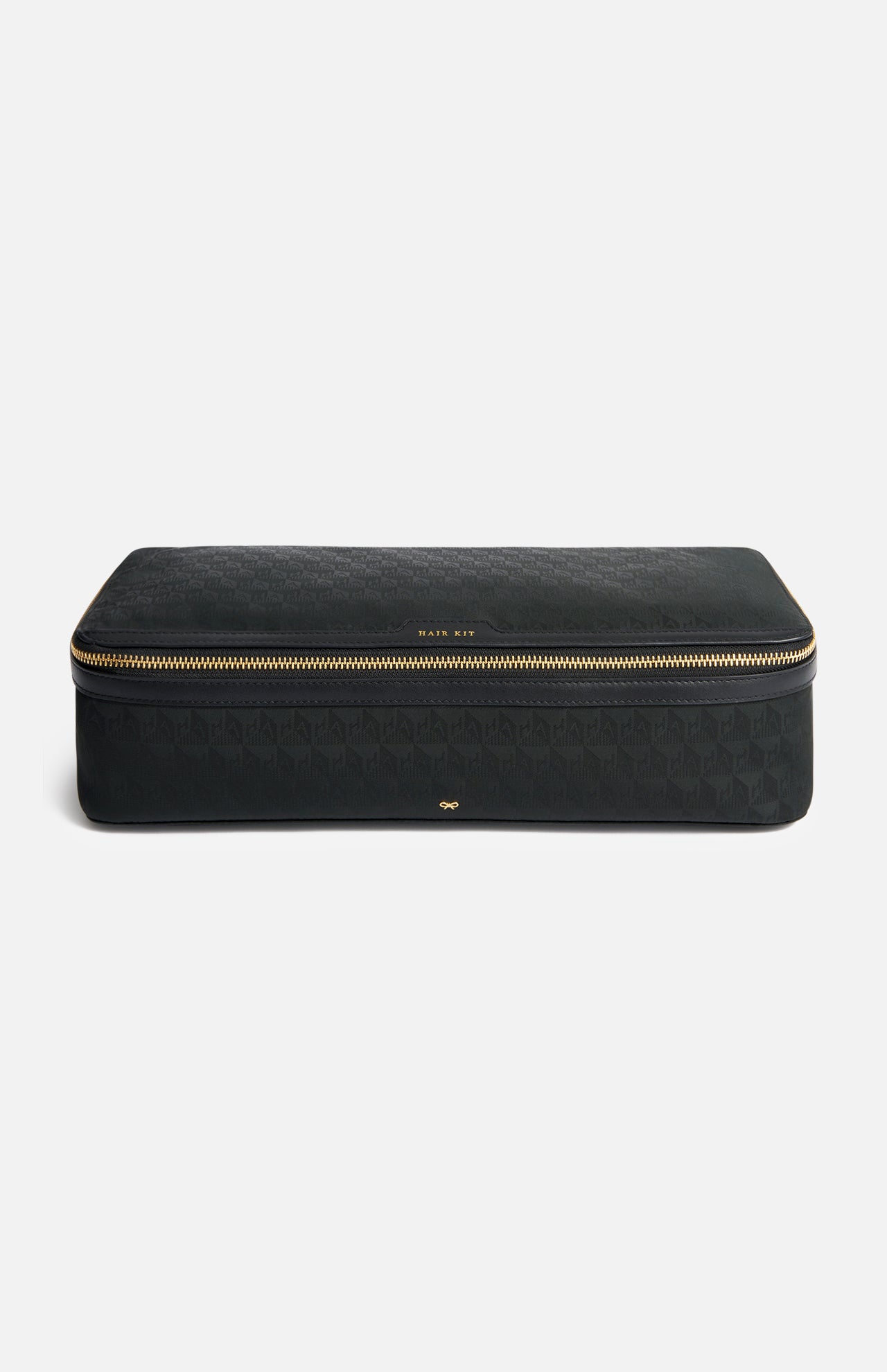 Anya Hindmarch Logo Hair Kit Travel Pouch, a black rectangular case with a wrap-around gold zipper and the text HAIR KIT centered on the front.