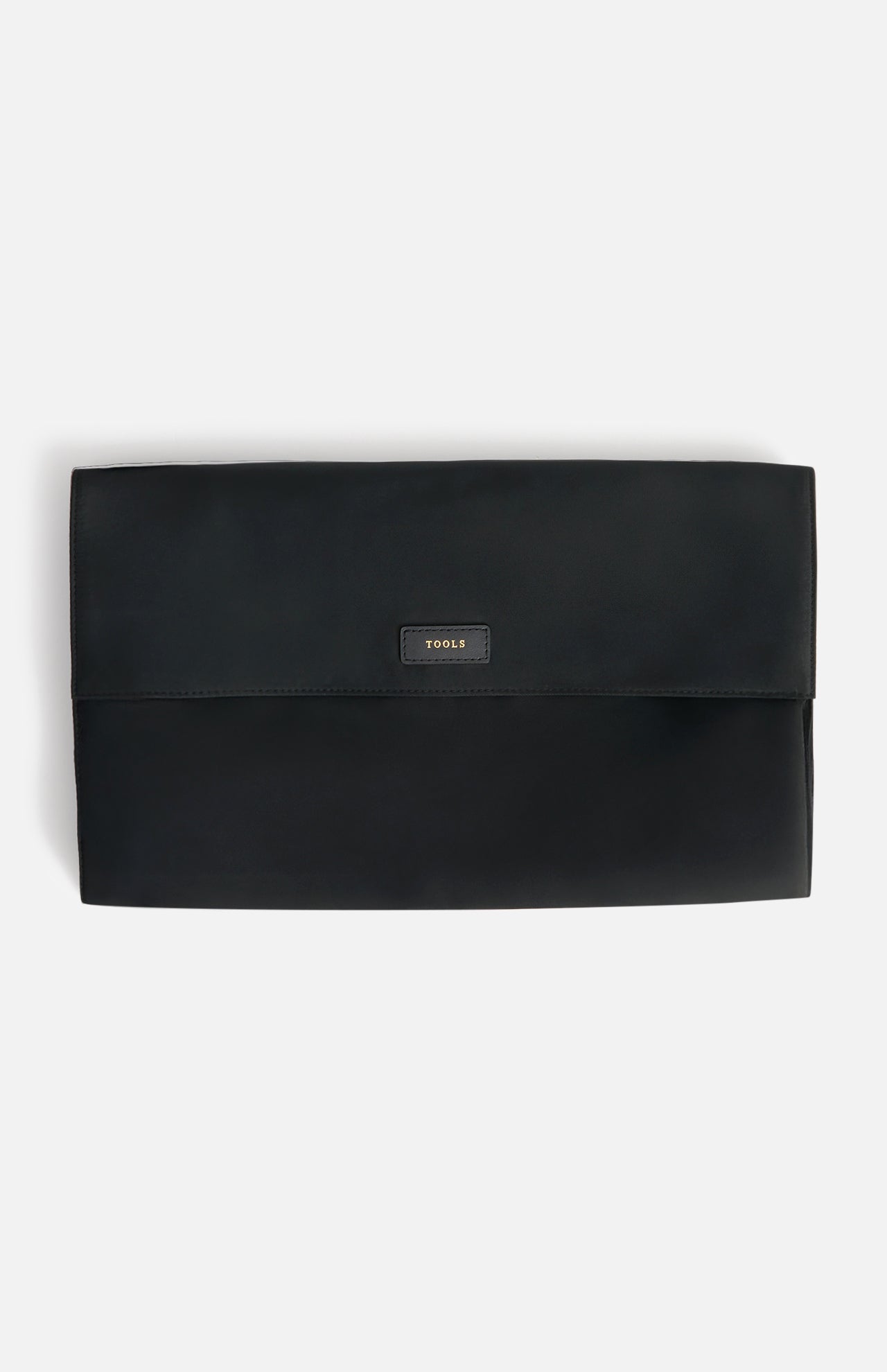 Black rectangular Anya Hindmarch Logo Hair Kit Travel Pouch with a flap closure, featuring a small patch embossed with the word TOOLS in gold lettering.