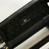 Anya Hindmarch Logo In-Flight Case in a clear design with black trim, gold-tone hardware, and a black interior lining featuring a bow logo and gold text.