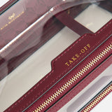 Anya Hindmarch Logo In-Flight Case, a clear rectangular travel accessory with burgundy leather trim, a gold-tone zipper, and the word TAKE-OFF embossed on the top tab.