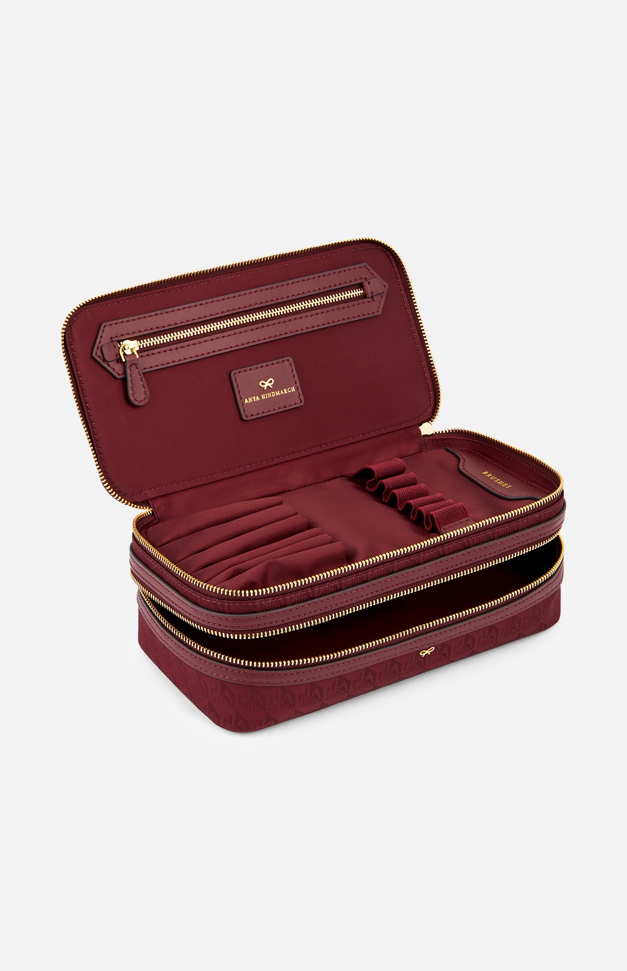 Open burgundy Anya Hindmarch Logo Make-Up Pouch revealing internal elastic brush holders and a zippered pocket, crafted with Italian organizational compartments.