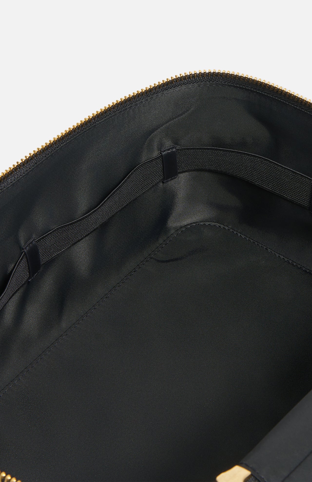 Interior of a black zippered Anya Hindmarch Logo Vanity Kit, showing an elasticized storage strap along the side of the luxury toiletry bag.