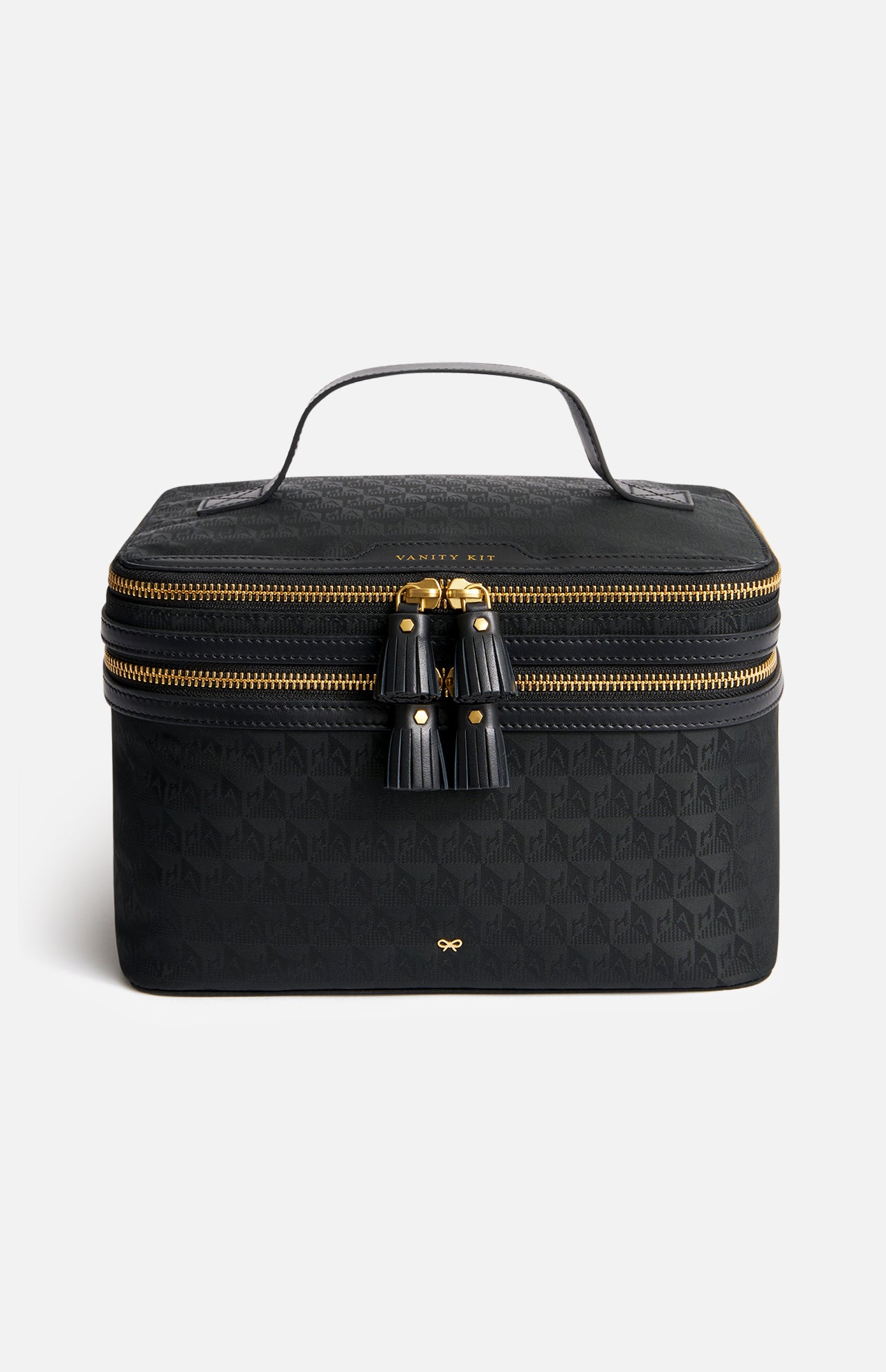Black Anya Hindmarch Logo Vanity Kit with a top handle, a double-zippered closure with two leather tassels, and a gold-tone bow emblem on the front.