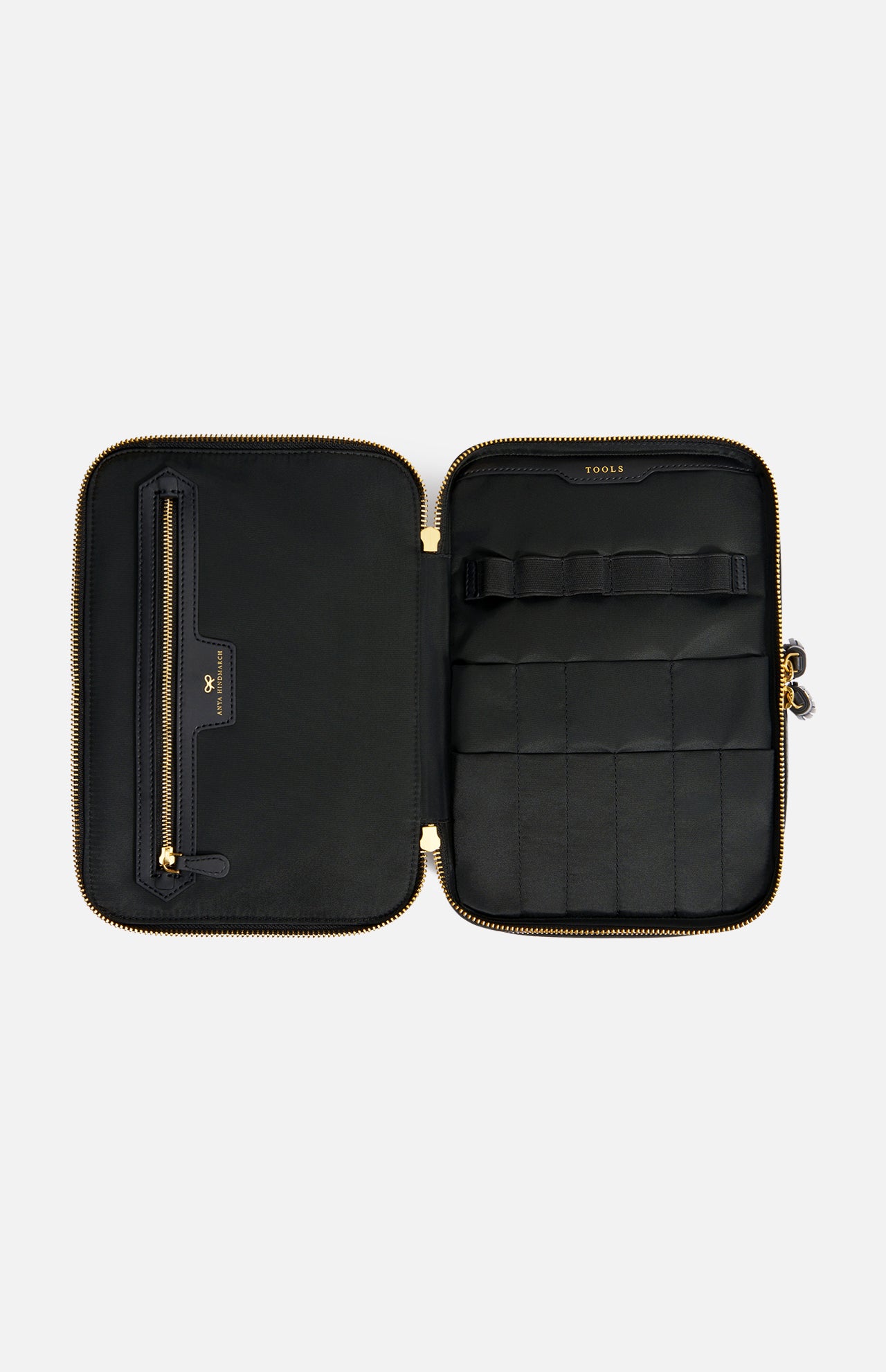 Open black zip-around Anya Hindmarch Logo Vanity Kit with an interior zippered pocket and elastic loops labeled TOOLS.