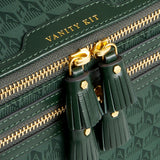 Anya Hindmarch Logo Vanity Kit in dark green with a repeating monogram pattern, gold-tone zipper pulls with tassels, and the words VANITY KIT embossed in gold.