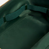 The interior of a dark green Anya Hindmarch Logo Vanity Kit, featuring a zippered pouch with an elastic loop strap along the back wall.
