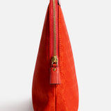 Side view of a bright red, Italian-made Anya Hindmarch Lotions and Potions Pouch featuring a zippered closure with a tassel pull.
