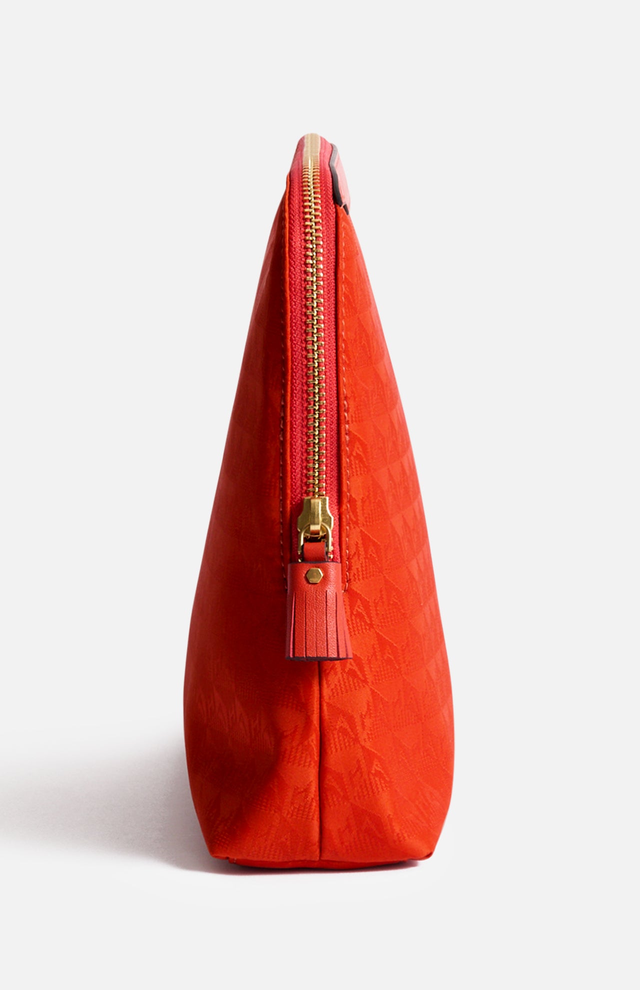 Side view of a bright red, Italian-made Anya Hindmarch Lotions and Potions Pouch featuring a zippered closure with a tassel pull.