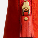 Close-up of a red Anya Hindmarch Lotions and Potions Pouch featuring a gold-toned metal zipper pull with a matching red leather tassel.