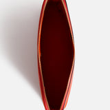 Top-down view of an open red Anya Hindmarch Lotions and Potions Pouch with a zipper.