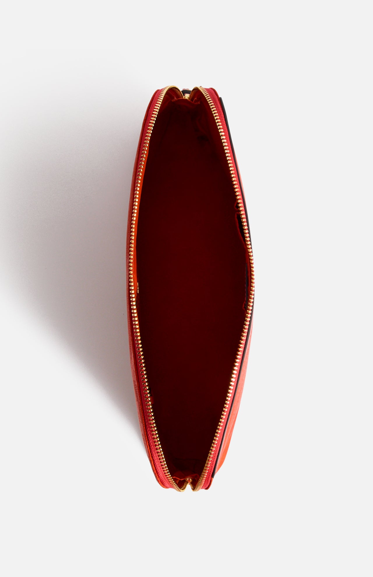Top-down view of an open red Anya Hindmarch Lotions and Potions Pouch with a zipper.