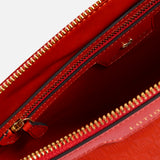 The interior of a red, Italian-made Anya Hindmarch Lotions and Potions Pouch, featuring a main compartment and an additional internal zippered pocket.