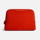 Red zippered Anya Hindmarch Lotions and Potions Pouch featuring a repeating geometric pattern and the words LOTIONS & POTIONS embossed in gold on the top trim.