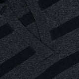 Close-up of the Allen Wool Cashmere Oversized Sweater in dark grey and black charcoal stripes, featuring a collar and v-shaped neckline. A visible white tag on the collar displays the brand name ARLO MOTT.