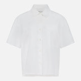 The ARLO MOTT Clark Split Back Top is a white poplin shirt with short sleeves, a classic collar, front pocket, and Mother of Pearl buttons. Shown on a plain white background.