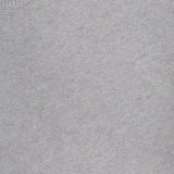 A close-up of the Clarkson Short Sleeve Crewneck Shirt by ARLO MOTT, a minimalist light grey knit with a ribbed neckline. A white clothing label reading ARLO MOTT is sewn into the collar of this Italian wool blend top.