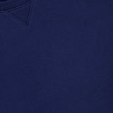 Close-up of the Kent Crew Neck Snaps Sweater in navy by ARLO MOTT, featuring a ribbed collar, V-shaped stitch detail, and a visible white brand tag at the neckline—an essential fashion-forward pullover.