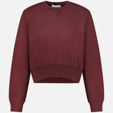 The ARLO MOTT Kent Crewneck with Side Snaps is a berry-colored, maroon cropped sweatshirt featuring long sleeves and ribbed cuffs, hem, and neckline, shown against a plain white background.