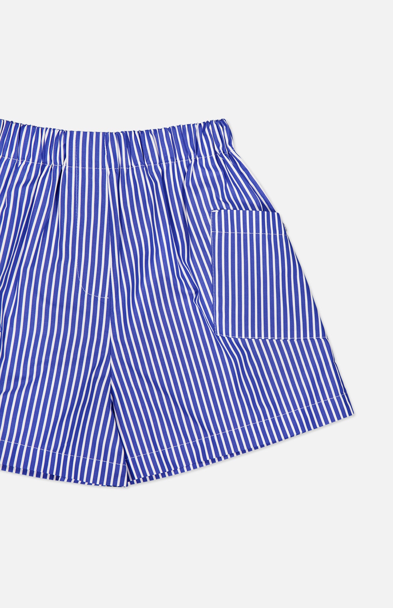 The Laight Striped Pocket Shorts by ARLO MOTT are high-rise blue striped shorts in crisp Portuguese poplin, featuring an elastic waistband and a right square pocket, shown on a white background.